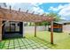 A backyard featuring green turf, a wooden pergola, and a custom bar and lounge area at 12215 Blue Pacific Dr, Riverview, FL 33579