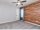 This bedroom features gray carpet, wood accent wall, ceiling fan and window with drapes at 12215 Blue Pacific Dr, Riverview, FL 33579