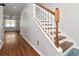 Bright hallway with wooden floors, staircase with white banister and view into the living room at 12215 Blue Pacific Dr, Riverview, FL 33579