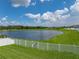 Scenic backyard view with a white fence and a gate overlooking a tranquil lake on a sunny day at 12931 Twin Bridges Dr, Riverview, FL 33579