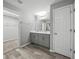 Bathroom featuring a double vanity, wood look flooring and a view into the adjacent walk in closet at 12931 Twin Bridges Dr, Riverview, FL 33579