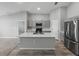 Kitchen island with sink, gray cabinets, stainless steel appliances, and a view to the living space at 12931 Twin Bridges Dr, Riverview, FL 33579