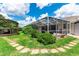 Expansive backyard with a charming gazebo, screened-in lanai, and stone pathway amidst green lawn and landscaping at 14096 Pullman Dr, Spring Hill, FL 34609