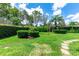 Beautifully landscaped backyard with lush green lawn, manicured hedges, and stone paver pathway at 14096 Pullman Dr, Spring Hill, FL 34609