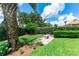Secluded backyard with mature trees, hedge, brick pathway and white bench at 14096 Pullman Dr, Spring Hill, FL 34609