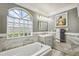Bright bathroom features a soaking tub, vanity, custom mirror, and natural light from the decorative glass block window at 14096 Pullman Dr, Spring Hill, FL 34609