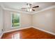 Neutral bedroom with hardwood floors, ceiling fan, and double-hung window with view to greenery at 14096 Pullman Dr, Spring Hill, FL 34609
