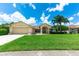Well-maintained front yard featuring lush green grass, mature palm trees and an inviting exterior at 14096 Pullman Dr, Spring Hill, FL 34609