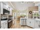 Well-lit kitchen featuring white cabinets, stainless steel appliances, tile backsplash, tile flooring and an adjacent breakfast nook at 14096 Pullman Dr, Spring Hill, FL 34609