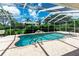 Screened-in pool with waterfall feature is surrounded by lush landscaping and paver decking at 14096 Pullman Dr, Spring Hill, FL 34609