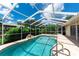 Sparkling screened-in pool with waterfall feature, surrounded by a spacious patio and lush landscaping at 14096 Pullman Dr, Spring Hill, FL 34609