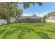 Spacious backyard featuring a large tree, lush green grass, and screened-in porch with furniture at 1513 Loretta Ct, Brandon, FL 33511