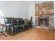 Inviting living room with a stone fireplace, dark leather seating, and wood flooring at 1610 Sanderling Ct, Brandon, FL 33511