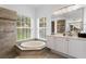 Bright bathroom featuring a corner tub, a glass enclosed shower, and a double sink vanity at 17807 Arbor Greene Dr, Tampa, FL 33647