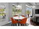 Cozy breakfast nook with orange chairs, a modern table, and a view of the screened pool area at 17807 Arbor Greene Dr, Tampa, FL 33647