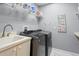 Functional laundry room with modern washer and dryer, storage shelves, and sink at 17807 Arbor Greene Dr, Tampa, FL 33647