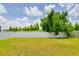 A well-maintained backyard featuring a white privacy fence, backing onto green space and mature trees at 18508 Merseyside Loop, Land O Lakes, FL 34638