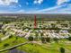 Aerial view showcases the property amidst a community of houses, green spaces, and a small lake at 18549 Grand Club Dr, Hudson, FL 34667