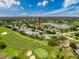 Aerial view of the property surrounded by a lush golf course, trees, and a serene lake at 18549 Grand Club Dr, Hudson, FL 34667