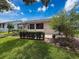 Exterior view of the back of the home showing lovely lawn, landscaping, and access to the patio at 18549 Grand Club Dr, Hudson, FL 34667