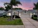 Charming single-story home featuring a well-manicured lawn, palm trees, and a two-car garage at 18549 Grand Club Dr, Hudson, FL 34667