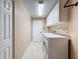 Bright laundry room with a washer, dryer, white cabinets and a door to outside at 18549 Grand Club Dr, Hudson, FL 34667