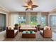 Bright sunroom featuring a leaf ceiling fan, tile flooring, comfortable wicker seating, and a glass coffee table at 18549 Grand Club Dr, Hudson, FL 34667