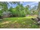 Spacious backyard with lush green grass, mature trees, and a wooden fence at 2108 E Linebaugh Ave, Tampa, FL 33612