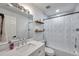 Bright bathroom featuring a shower and tub combination, white walls, floating shelves, and marble accent tiles at 2108 E Linebaugh Ave, Tampa, FL 33612