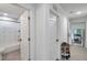 Hallway with doors to a bathroom and kitchen with tile floors and white walls at 2108 E Linebaugh Ave, Tampa, FL 33612