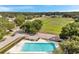 Aerial view of a community pool with clear blue water and ample deck space surrounded by lush landscaping and an adjacent field at 243 Chardonnay Pl, Valrico, FL 33594