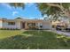 Beautiful single-story home with a well-manicured lawn, a porch and a golf cart at 245 Grove Cir N, Dunedin, FL 34698