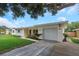 Well-maintained home with a white garage door, lush lawn, and inviting entryway at 245 Grove Cir N, Dunedin, FL 34698