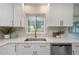 Bright kitchen features white cabinets, stainless steel appliances, quartz countertops, and backyard views at 245 Grove Cir N, Dunedin, FL 34698