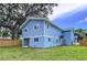 View of blue two-story home, showcasing the backyard and complemented by lush greenery at 309 Congress St, Oldsmar, FL 34677