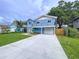 Inviting two-story home featuring an attached garage, a well-manicured lawn and a long driveway at 309 Congress St, Oldsmar, FL 34677