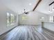 Bright, open-plan living room with vaulted ceilings, wood beam, and gray wood-look floors at 309 Congress St, Oldsmar, FL 34677