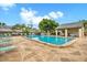 Community pool with lounge chairs, tables, and covered seating area with blue skies in the background at 3151 Landmark Dr # 115, Clearwater, FL 33761