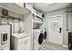 Laundry room with utility sink, modern washer and dryer, shelving, and door to the outside at 34215 Kiefer Rd, Dade City, FL 33525