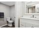 Clean bathroom featuring a toilet and modern vanity with sink, bright lighting and grey walls at 4510 Overlook Ne Dr # 224, St Petersburg, FL 33703