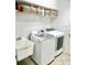 Efficient laundry room with modern washer and dryer, sink, and ample storage space on shelves at 4745 Trout River Xing, Ellenton, FL 34222