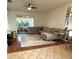 A spacious living room with tile and wood flooring, a sectional sofa, and sliding glass doors to the patio at 4745 Trout River Xing, Ellenton, FL 34222