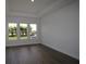 Minimalist bedroom with tray ceiling, dark hardwood floors, large windows, and bright white walls at 5033 Chapel Row Ave, Apollo Beach, FL 33572