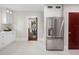 Open kitchen with stainless steel refrigerator, white cabinets, tile floors, and dark red door at 5518 21St S Ave, Gulfport, FL 33707