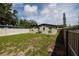 View of the back of the home showing grass, small trees, and vinyl fencing at 5519 Kelly N Dr, St Petersburg, FL 33703