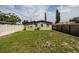 View of the home's back exterior with grass, vinyl fence and small trees at 5519 Kelly N Dr, St Petersburg, FL 33703