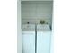 Laundry closet with a washing machine and dryer with overhead shelving at 6144 Elmhurst Dr, New Port Richey, FL 34653