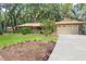 Charming stone home with a lush lawn, mature trees, and a long driveway leading to a two-car garage at 616 Pawn Way, Seffner, FL 33584