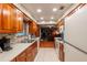 Galley kitchen featuring wood cabinets, stainless steel appliances, and a view of an adjacent living area at 616 Pawn Way, Seffner, FL 33584