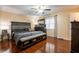 A spacious main bedroom featuring hardwood floors, fan, and a large dark wood furniture set at 616 Pawn Way, Seffner, FL 33584